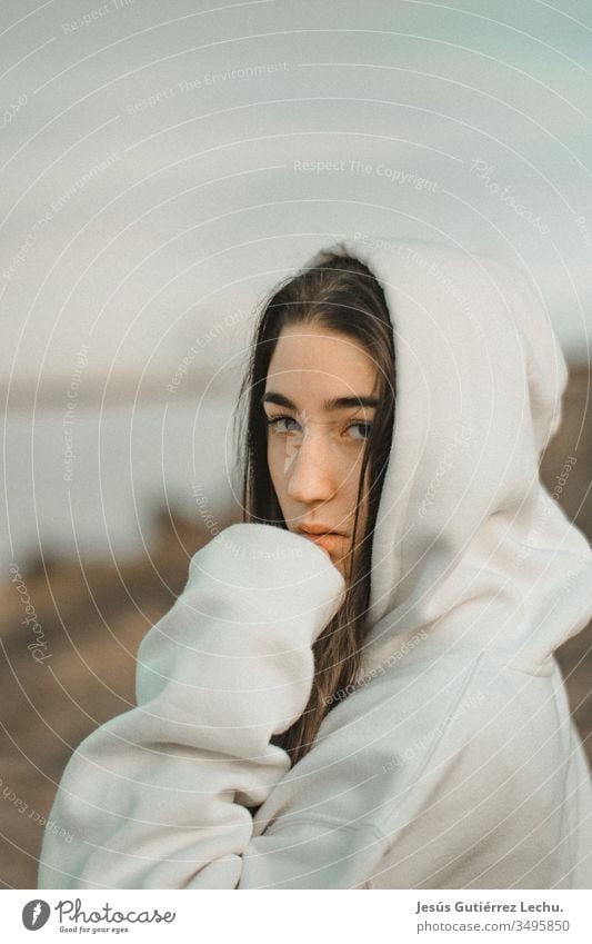 junge Frau mit Kapuze in einem weißen Sweatshirt mit ernstem Blick altehrwürdig Hintergrund Behaarung Gesicht Mädchen Menschen Außenaufnahme Beautyfotografie