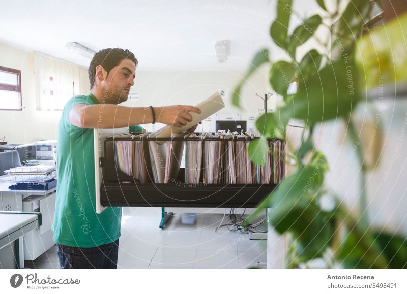 Büroangestellte im Büro, die in Schubladenordnern suchen Arbeiter Dateien Job Mann Dokumentation Arbeitsplatz Computer am Arbeitsplatz im Innenbereich