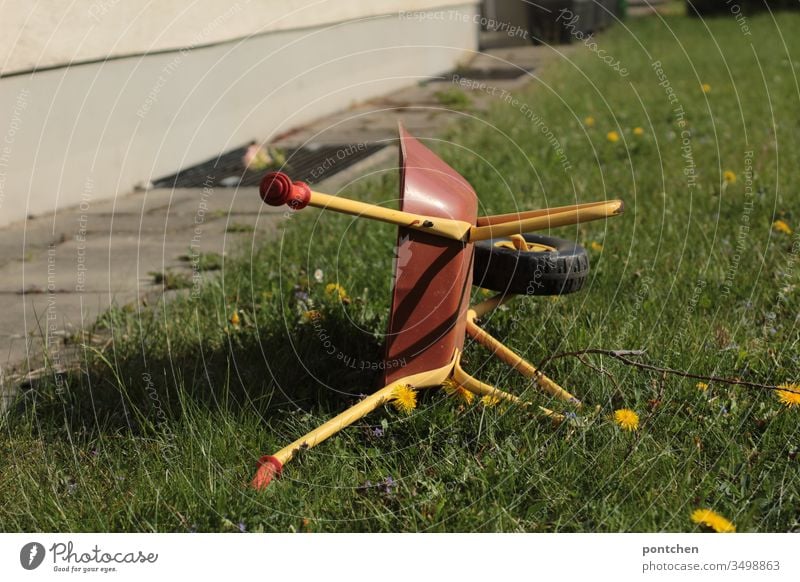 Kinderspielzeug Schubkarre steht hochkant auf einer Wiese. Gartenarbeit wiese löwenzahn grün natur hobby spielen gärtner Gärtner Gras Farbfoto Außenaufnahme