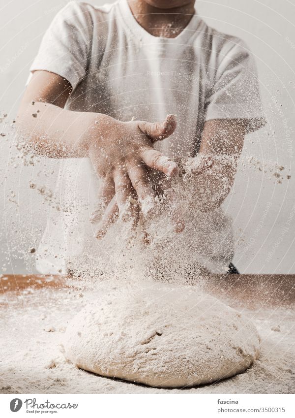 Zicklein, das mit Mehl über den Teig klatscht, senkrecht Ernte unkenntlich Kind Person Klatschen Hände während Essen zubereiten Brot Berieselung weiß vorbei