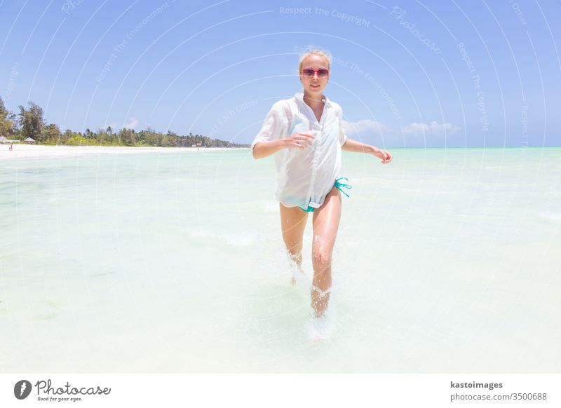 Junge aktive Frau, die Spaß am Laufen und Plantschen in Muschelseewasser hat. Strand MEER platschen Sommer Schönheit Mädchen im Freien schlank reisen tropisch