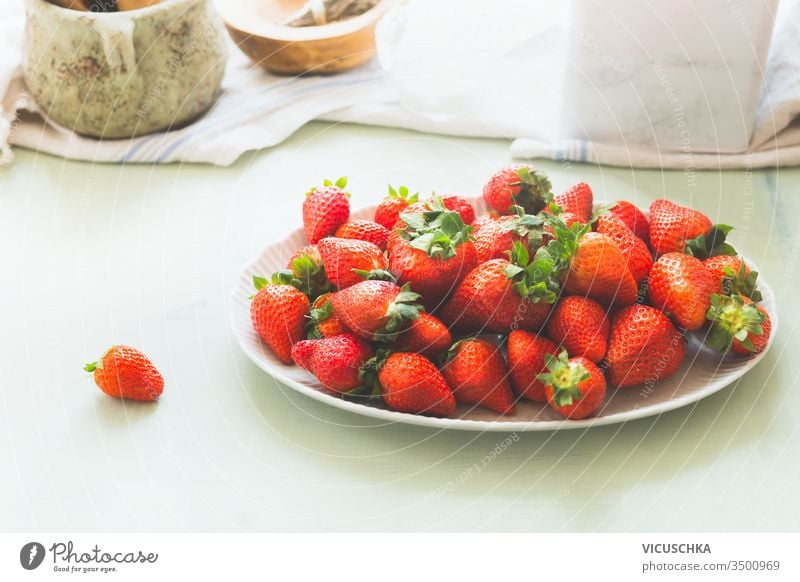 Bio-Gartenerdbeeren in weißer Platte auf hellem Küchentisch . Gesunde Nahrung der Saison. Haufen reifer Beeren organisch Teller Licht Tisch Gesundheit