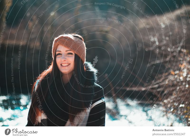 Bildnis einer attraktiven Brünetten in schwarzer Winterkleidung und orangem Stirnband. Kalter Wintertag im Wald, lächelndes Glück Erwachsener Herbst Hintergrund