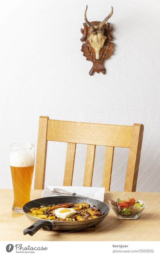 Tiroler Kartoffelgröstl mit Zwiebeln Gröstl Pfanne gebraten Herz Liebe Übersicht Speck Nahaufnahme Tisch Stuhl Geweih groestl Essen Fleisch Hintergrund Ei