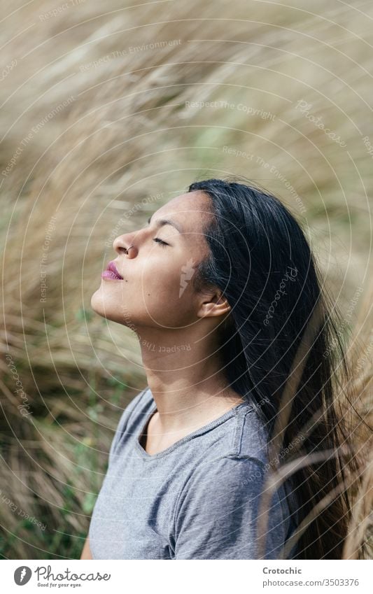 Porträt einer jungen brünetten Frau mit geschlossenen Augen beim Meditieren vertikal Ausdruck Gesicht Profil träumen Erhöhung Sonnenlicht Feld Natur bequem