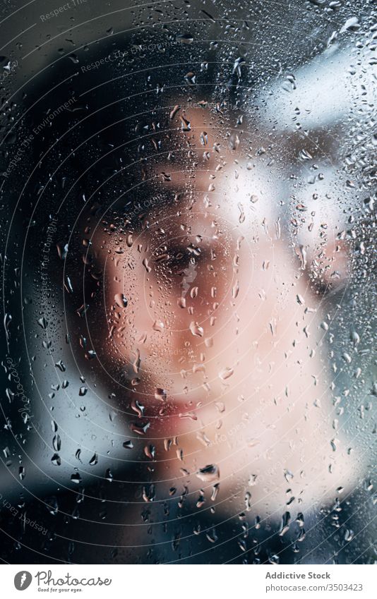 Nicht erkennbare Person hinter nassem Glas stehend traurig Depression Isolation Melancholie Einsamkeit unglücklich Stress verärgert einsam Regen Coronavirus