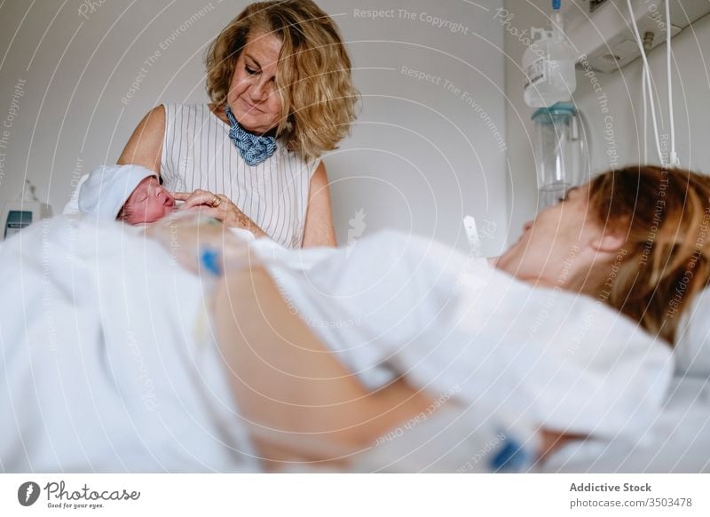 Frau besucht Tochter mit Neugeborenem im Krankenhaus neugeboren Baby Mutter Großmutter Frauen Pflege Bett besuchen Gruß Klinik Glück neonatal Kind Medizin