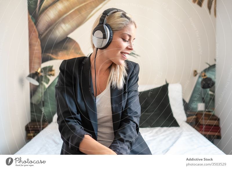 Fröhliche Frau hört Musik im Bett zuhören heimwärts Lächeln Kopfhörer Augen geschlossen modern Schlafzimmer Glück Headset heiter jung Klang Lifestyle Audio