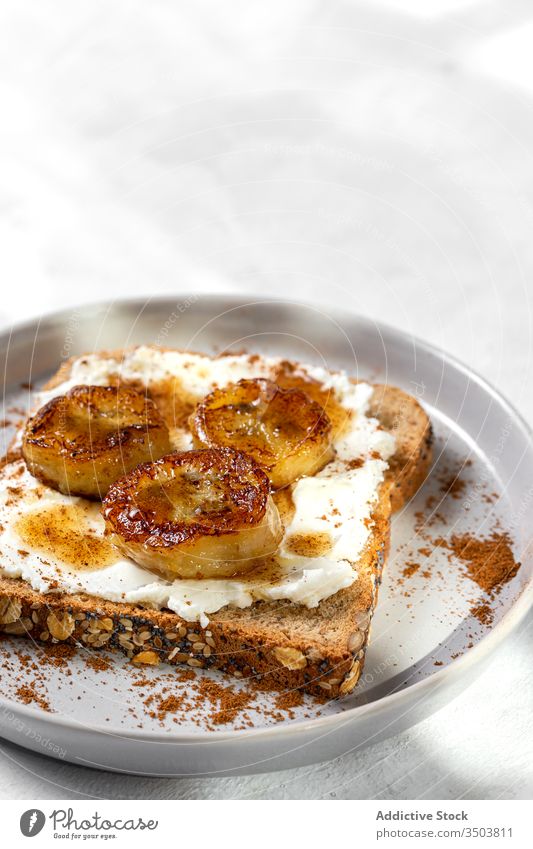 Hausgemachtes getoastetes Brot mit Frischkäse, gebratene Banane, Honig und Lebensmittel Belegtes Brot Zuprosten gebratener Wegerich Liebling Zimt Gesundheit