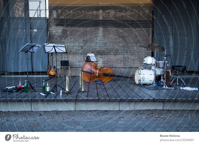 menschenleere Konzertbühne mit Notenständern, Gitarre, Trompete, Kontrabass und Schlagzeug Menschenleer notenständer Getränkeflaschen Musik Show Backsteinwand