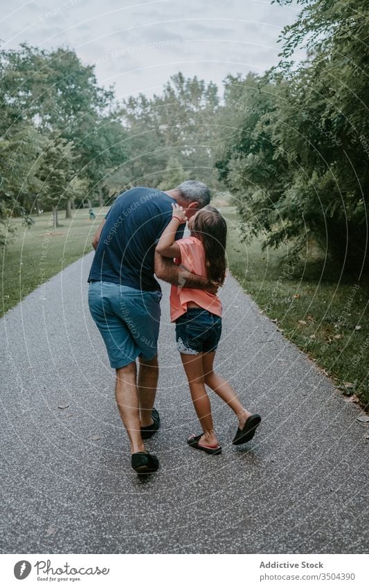 Vater mit Tochter geht im Park spazieren geheim hauchen Zusammensein Spaziergang reden Partnerschaft Kind Kommunizieren Liebe Eltern Gespräch Umarmung lässig