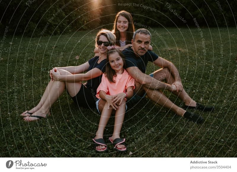 Glückliche Familie ruht sich auf der grünen Wiese aus Zusammensein Natur ruhen sich[Akk] entspannen sitzen Park Wald Landschaft Sommer Lächeln aktiv lässig Gras