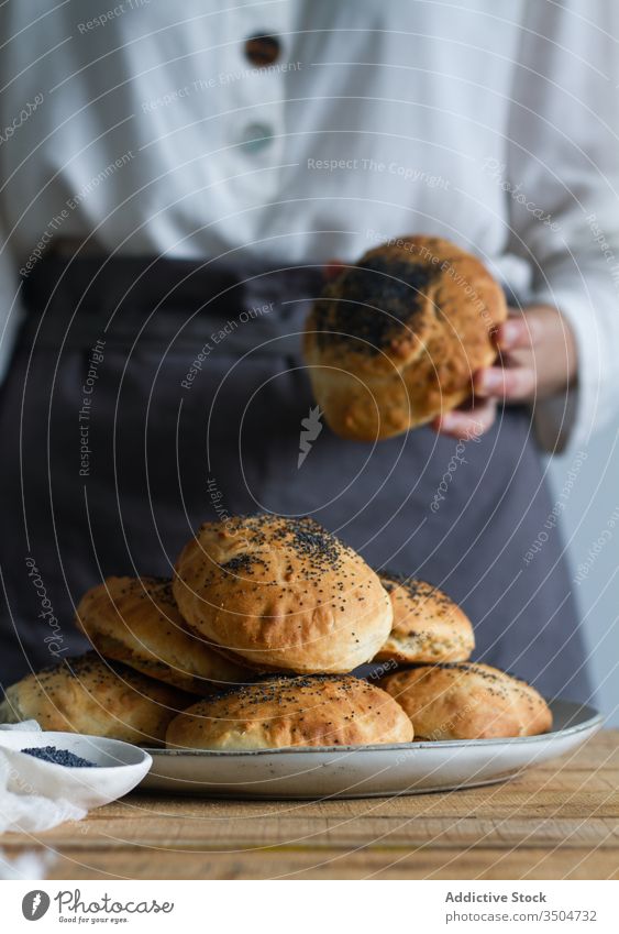 Pflanzenkoch mit frischen Brötchen Küchenchef Bäckerei Mohn Teller Samen Tisch vorbereiten Gebäck Lebensmittel lecker geschmackvoll Mahlzeit süß kulinarisch