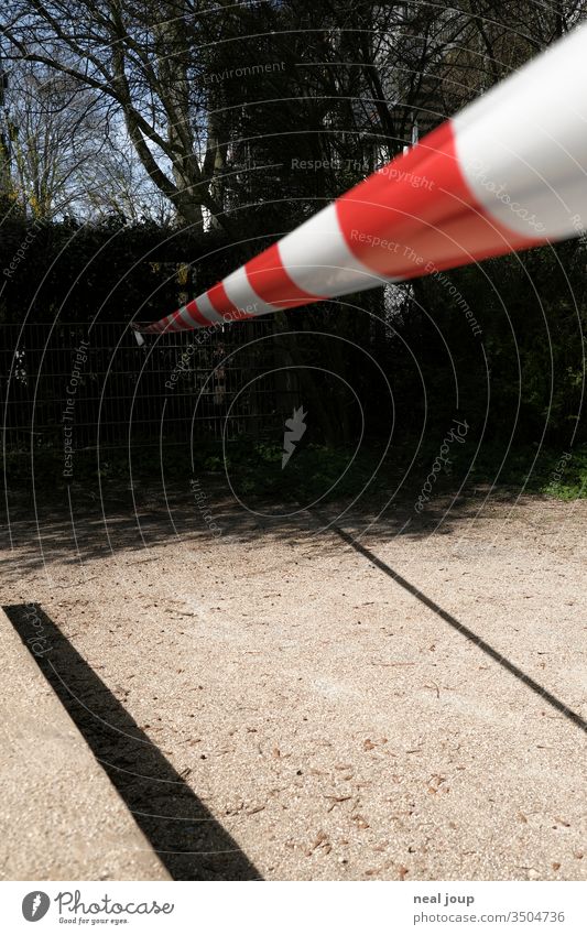 Absperrband ins Dunkle schatten spielplatz aussenaufnahme gesperrt abgesperrt verboten coronakrise isolation menschenleer depression abwarten rot-weiß farbfoto