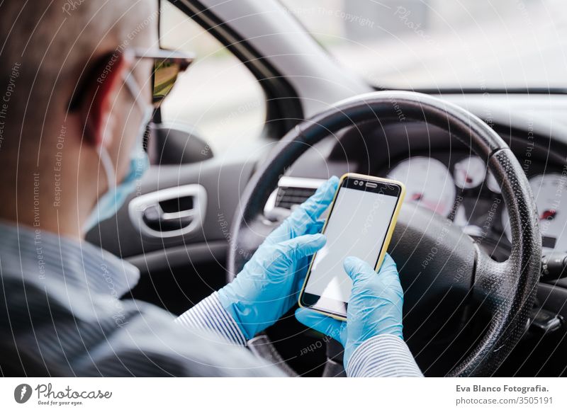 mann mit handy in einem auto mit schutzmaske und handschuhen während einer coronacirus-pandemie covid-19 Mann fahren PKW Schutzmaske Handy Schutzhandschuhe