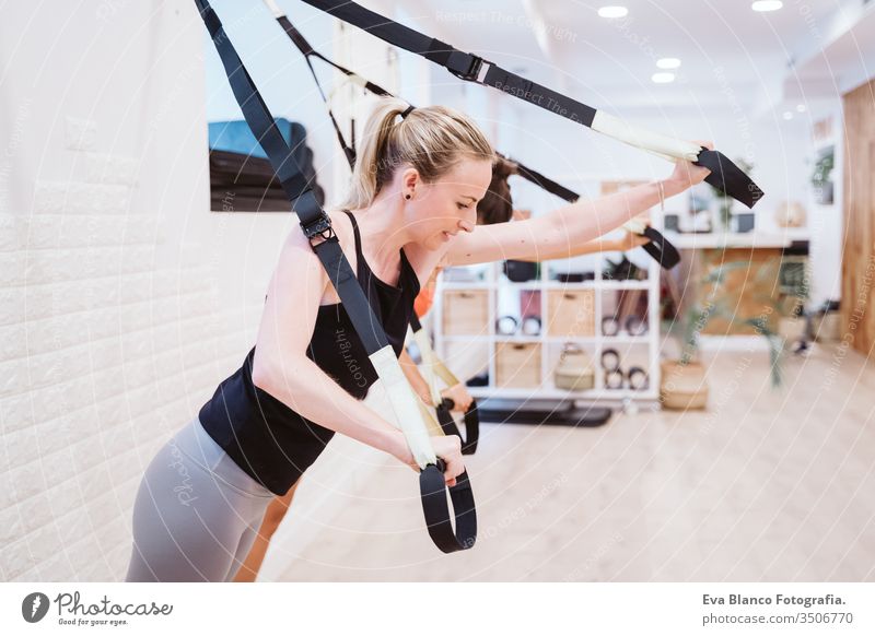 Gruppe von Frauen, die in der Turnhalle mit Trx Sport treiben. Gesunder Lebensstil Hanteln Fitnessstudio Freunde Gesundheit Lifestyle im Innenbereich Training