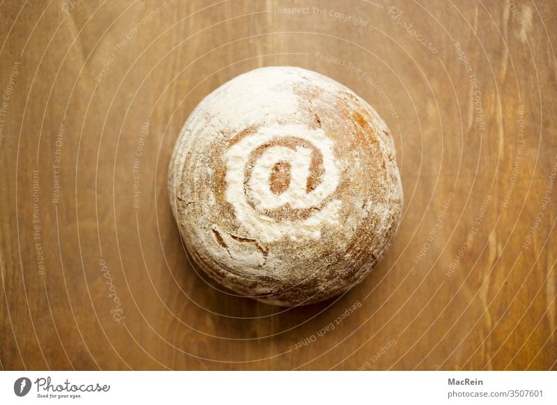 At-Zeichen mit Mehl auf einem Brot dekoriert brot Brotlaib backen bäcker bäckerei backware nahrungsmittel rund tisch vollkornbrot mehl Onlinehandel at-zeichen