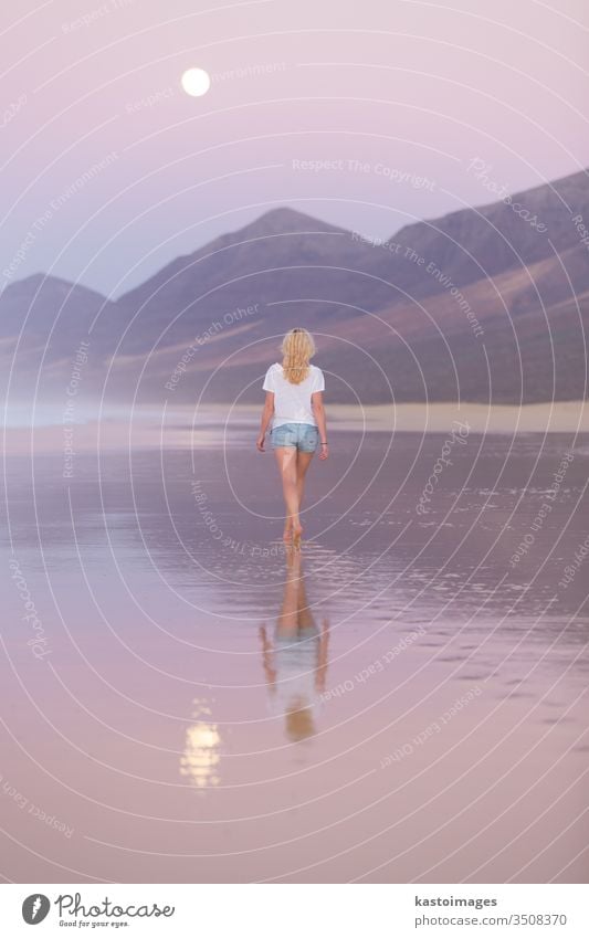 Dame beim Spaziergang am Sandstrand im Sonnenuntergang. Frau MEER Strand Landschaft Küstenlinie Fußspur Fußtritt Urlaub Wasser Natur Sommer Mondschein Wellen