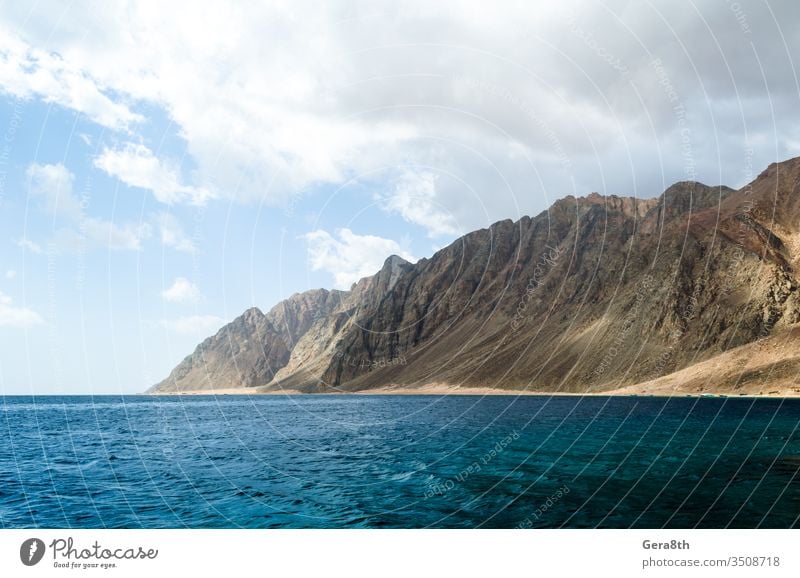 blaues Meer und hohe felsige Berge gegen den Himmel und Wolken in Ägypten Dahab Südsinai Naher Osten Rotes Meer Süd-Sinai Hintergrund Blaues Meer Tag hoch