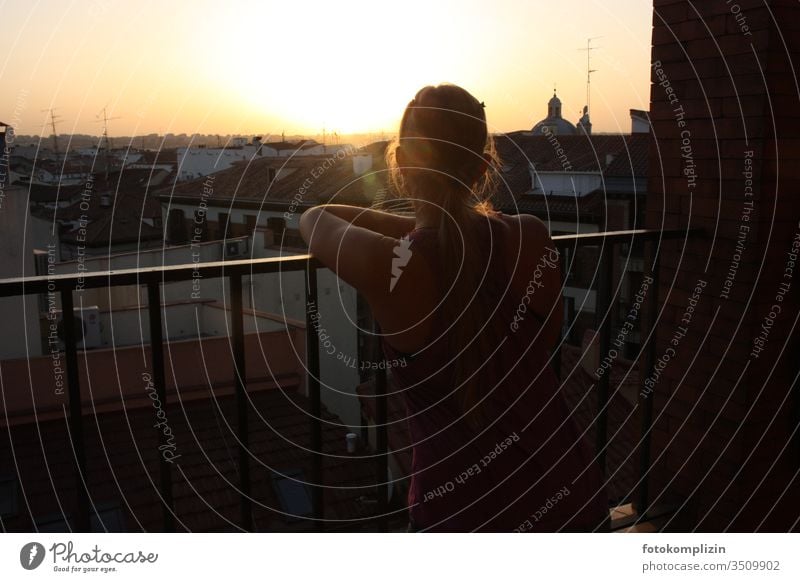 junge Frau blickt bei Abendsonne über Stadt-Dächer romantisch Aussicht Balkon Großstadt nachdenklich melancholie betrachtend Gegenlicht schauen urban Weitblick