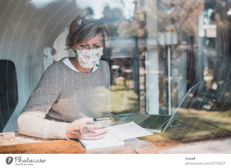 Frau mit Mundschutz und smartphone home office arbeiten laptop Telefon handy zuhause Zimmer Maske Haus blond Rechner Computer Quarantäne Technologie entspannt