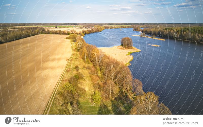 Frühlingswindiger Tag. Plätschert auf dem Wasser. Fluss mit Insel-Luftaufnahme. Wind kräuselt See Flussufer Wetter Stausee Antenne Wolken grün ländlich Pflanze