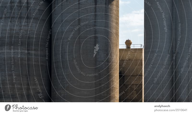 Silos aus massivem Beton und ein in der Sonne stehender Schornstein abstrakt Architektur Hintergrund beton Blauer Himmel Gebäude Gebäudeaußenseite