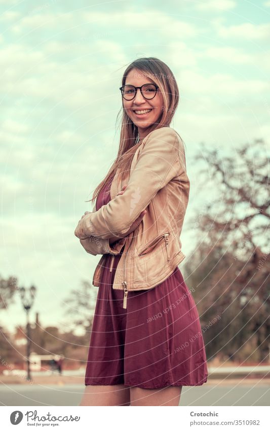 Porträtfoto eines Mädchens mit langen Haaren und Brille in einem lila Kleid in einem Park vertikal Lächeln Ausdruck Gesicht drehen. elegant Frau jung feminin