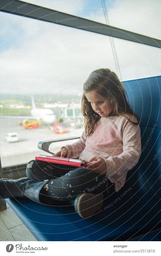 Kleines süßes Mädchen wartet am Flughafenterminal auf das Flugzeug und benutzt ein digitales Tablett Kind bezaubernd Fluggerät Fluggesellschaft Kaukasier Stuhl