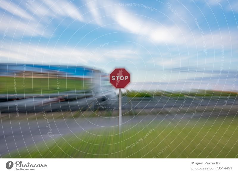 "Stopp"-Verkehrszeichen und ein fahrender Lastwagen auf der Straße, alles unter einem Zoom-Effekt Verkehrsgebot stoppen Zeichen Stoppschild Symbol Ermahnung