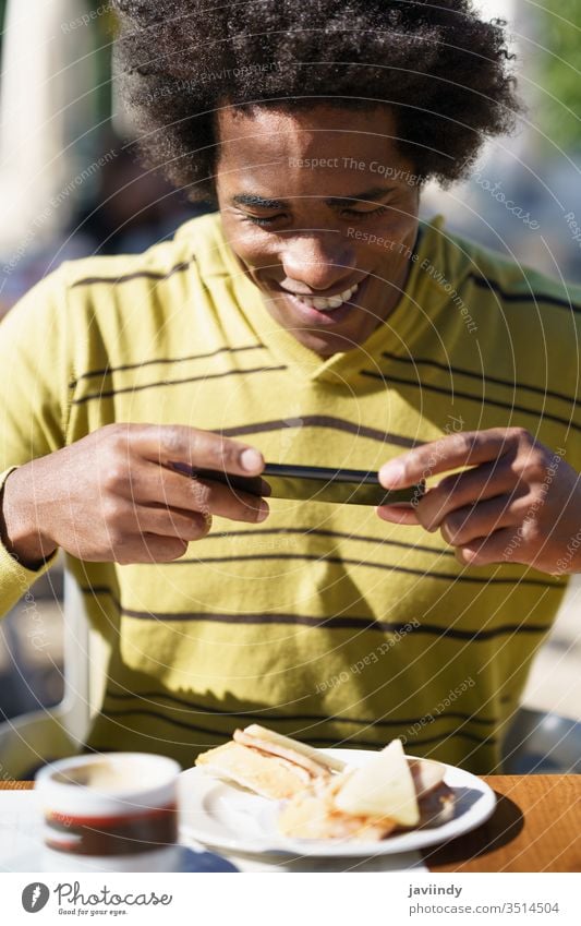 Kubanischer Schwarzer beim Fotografieren mit seinem Smartphone zu einem Imbiss Mann Afro-Look schwarz Behaarung Afrikanisch tausendjährig männlich Person lässig