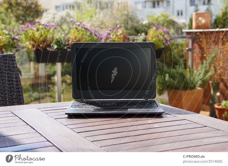 Laptop auf Terrassentisch vor Blumen Notebook Computer Outdoor Balkon Blumenkasten Homeoffice Frühling draußen arbeiten Büro