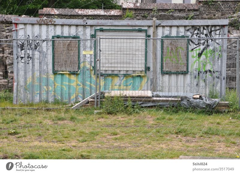 verrammelter Baucontainer Baubude Container Graffiti Ödland Brachland BAustelle zaun geschlossen verriegelt vergittert tristesse Wellblech Bauzaun Öde Rolladen