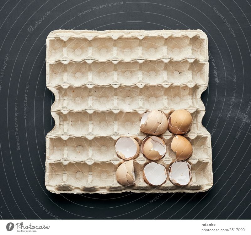 Eierschale in einem Papiertablett auf einem schwarzen Holztisch Bauernhof Feder Lebensmittel Zerbrechlichkeit gebrochen Hintergrund Vogel Holzplatte Frühstück