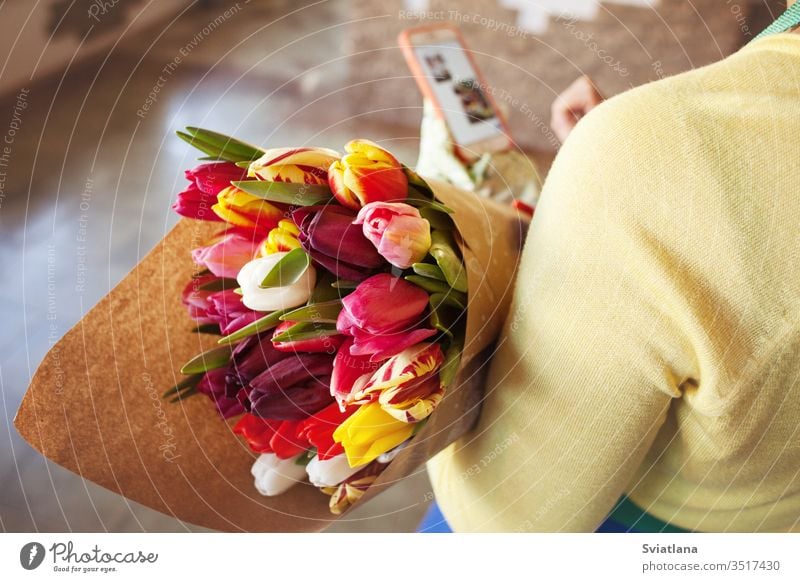 Der Verkäufer hält einen großen, schönen Tulpenstrauß, verpackt in Bastelpapier. Ansicht von oben Blumenstrauß Hände Papier Art rosa Verpackung geblümt