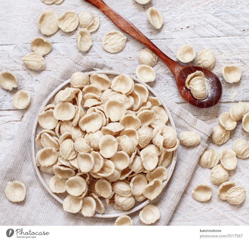 Frische rohe italienische Teigwaren Orecchiette Apulien Spätzle Italienisch frisch trocknen traditionell Bestandteil Draufsicht Messer dunkel Teller Diät Mehl