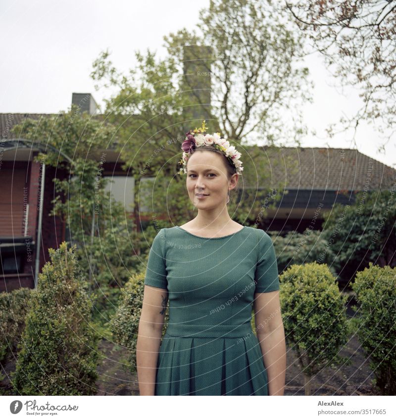 Analoges Portrait einer jungen Frau mit Blumenkranz im Garten schön sportlich schlank Schaukel grün Pflanze Hecke Stäucher Baum Natur Gartenfee Farbfoto