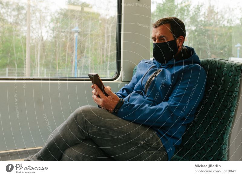 Mann mit Stoffmaske oder Mund-Nasen-Schutz im öffentlichen Verkehr während Coronavirus Pandemie Ausbruch Gesichtsmaske Maske Mund-Nasen-Maske S-Bahn Zug