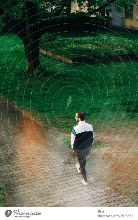 Ein Mann in lustigen Sportklamotten, der einen Weg entlang geht gehen Natur Stimmung grün Passant spazieren Sportkleidung Wohnanlage draußen Tag Spaziergang