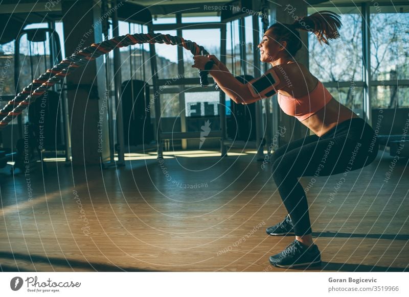 Junge Frau mit Kampfseilübung in der Fitnesshalle muskulös Stärke Athlet Fitnessstudio Seil Lifestyle Schlacht Sport passen Training Körper aktiv jung