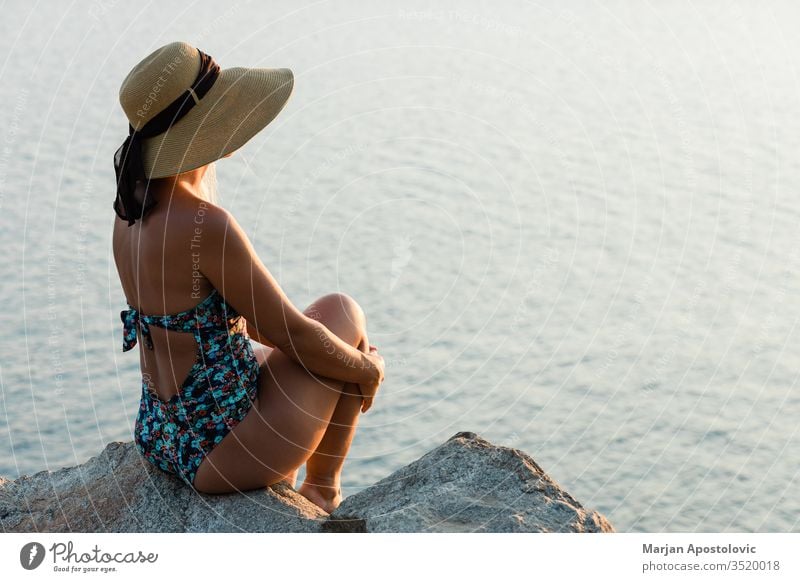 Junge Frau genießt Sonnenuntergang am Meer Abenteuer schön Schönheit sorgenfrei Klippe Küste Küstenstreifen Küstenlinie genießend Abend Freiheit Mädchen Hut