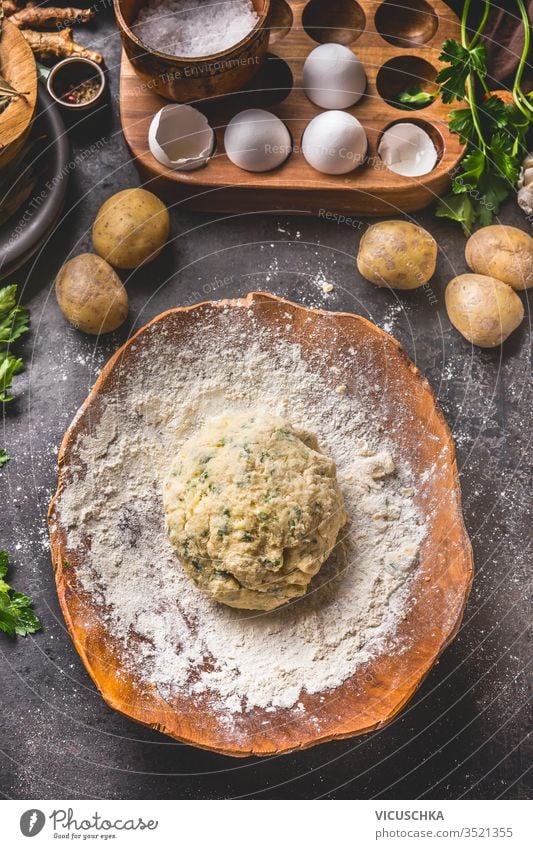 Hausgemachter Kartoffelteig in Holzschüssel mit Mehl und Eiern auf dunklem Küchentischhintergrund. Ansicht von oben. Zubereitung von Gnocchi. Schmackhafte Hausmannskost. Klassische Küche. Schmackhafte Hausmannskost.