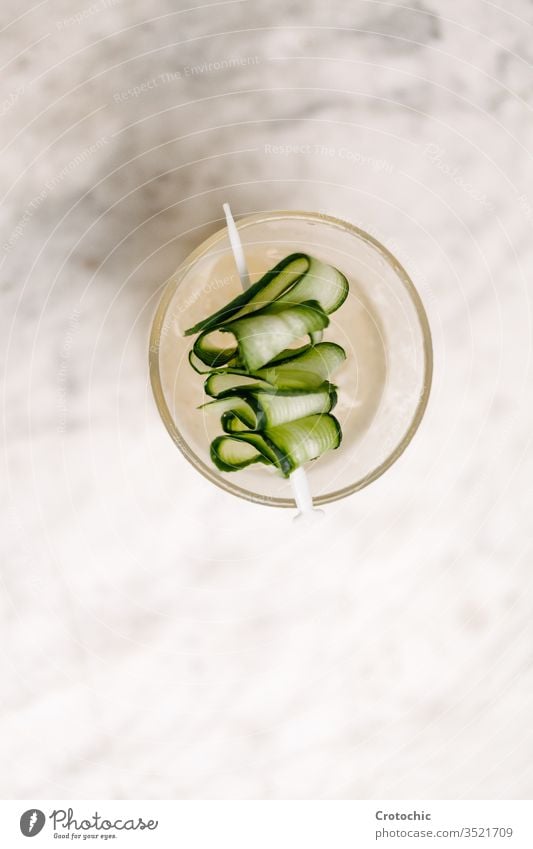 Teller mit einem Gurkenspieß auf weißem Hintergrund vertikal Antenne Gemüse Salatgurke Spieß Genuss Lebensmittel Lebensstile reich verdrehen Cocktail filigran