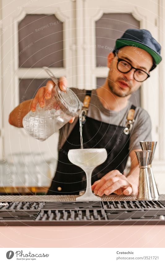 Vertikales Foto eines Kellners, der Flüssigkeit in ein Glas mit Eis in ein Frost-Cocktailglas umfüllt transferieren liquide Alkohol Bar Gießen Brille Minze