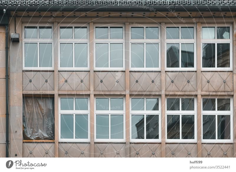 Das kaputte Fenster in der Fassade wurde mit Brettern und Plane verschlossen verrammeln verrammelt Verfall reperatur Sanieren alt Haus Vergänglichkeit