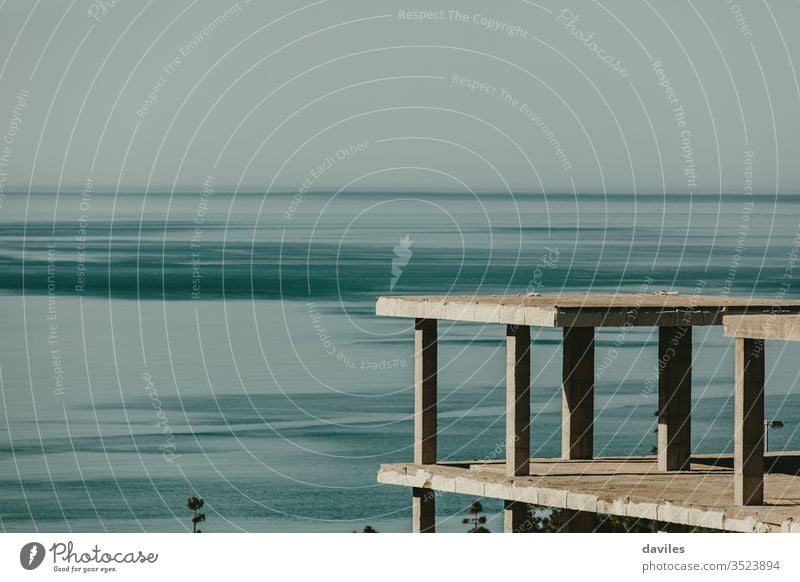 Hausbetonfundament auf der Spitze eines Hügels; mit dem Mittelmeer im Hintergrund. Aufgegebene Konstruktion. Konzept zur Wohnungs- und Immobilienkrise.