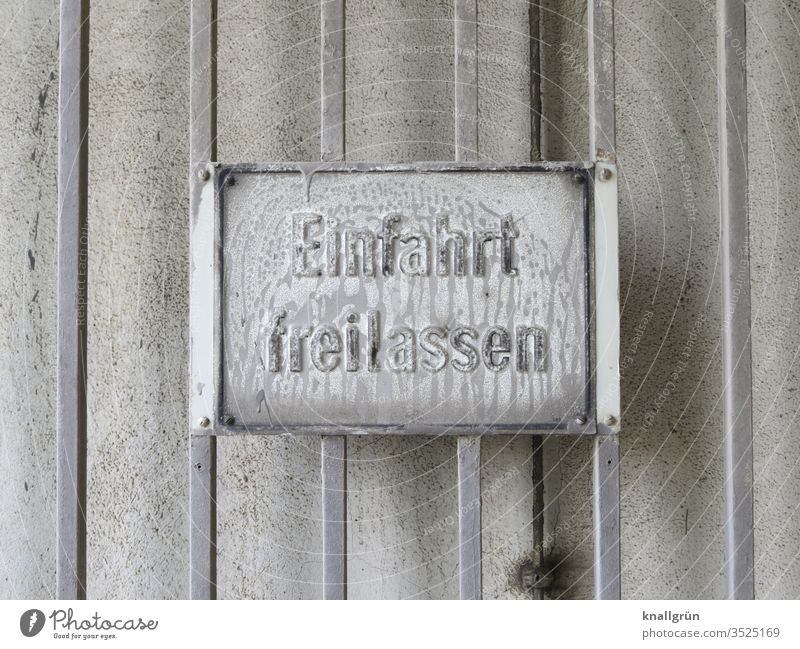 Weiß überpinseltes „Einfahrt freilassen“- Schild auf weiß gestrichener Metallwand Schilder & Markierungen Kommunizieren Hinweisschild Warnschild Außenaufnahme