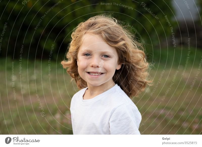 Lustiges blondes Kind mit langen Haaren. außerhalb eine Kindheit Menschen Kaukasier Freude Junge wenig Natur Behaarung wellig spielen Sommer jung im Freien Spaß