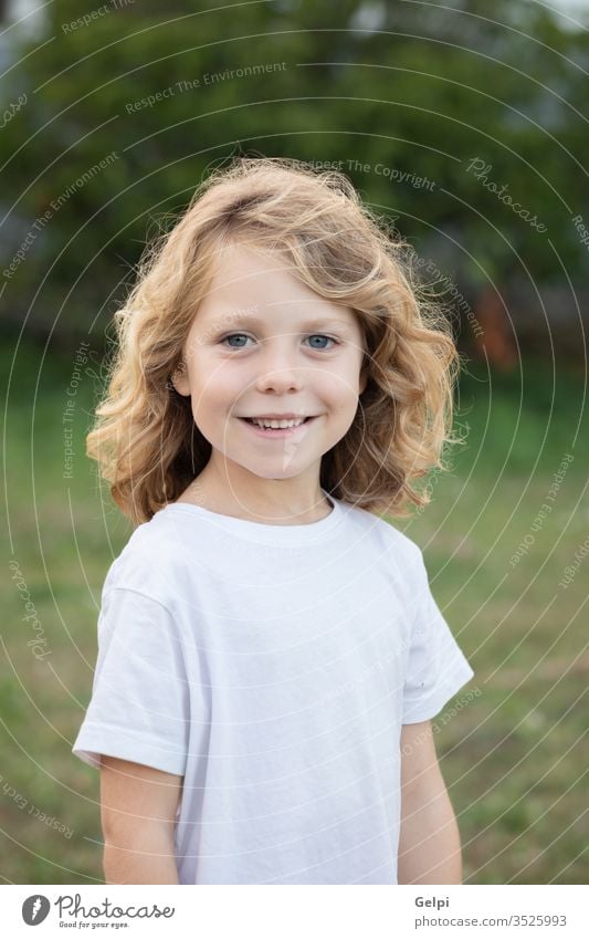 Lustiges blondes Kind mit langen Haaren. außerhalb eine Kindheit Menschen Kaukasier Freude Junge wenig Natur Behaarung wellig spielen Sommer jung im Freien Spaß