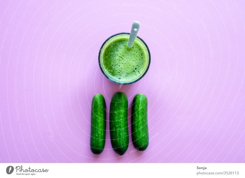 Frischer Gurkensaft in einem Glas und ganze Gurken auf einem rosa Hintergrund, Draufsicht klein Saftglas smoothie grün Detox Gesunde Ernährung Getränk Diät